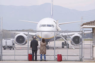Uns viatgers contemplen un avi estacionat a l'aeroport de Girona-Costa Brava. <br/>